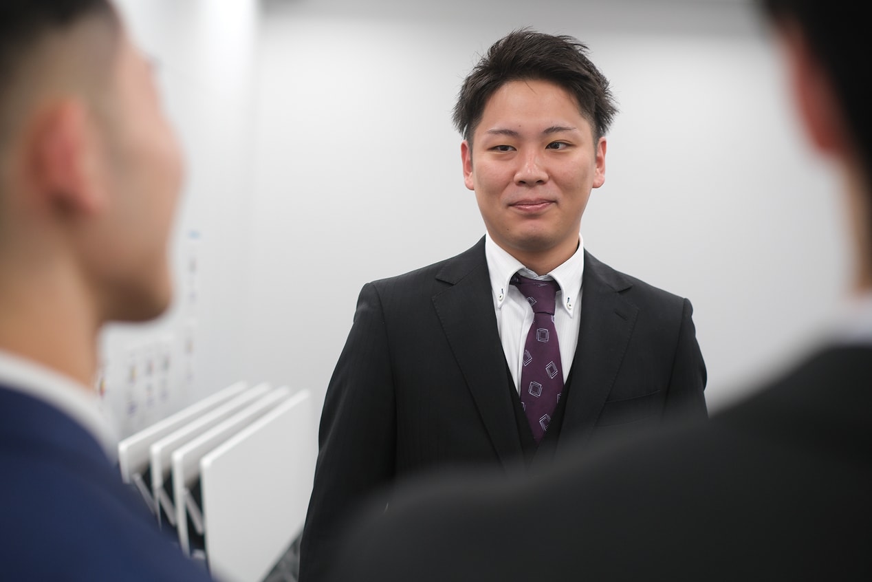 スーツ姿の男性社員が笑顔で会話している様子
